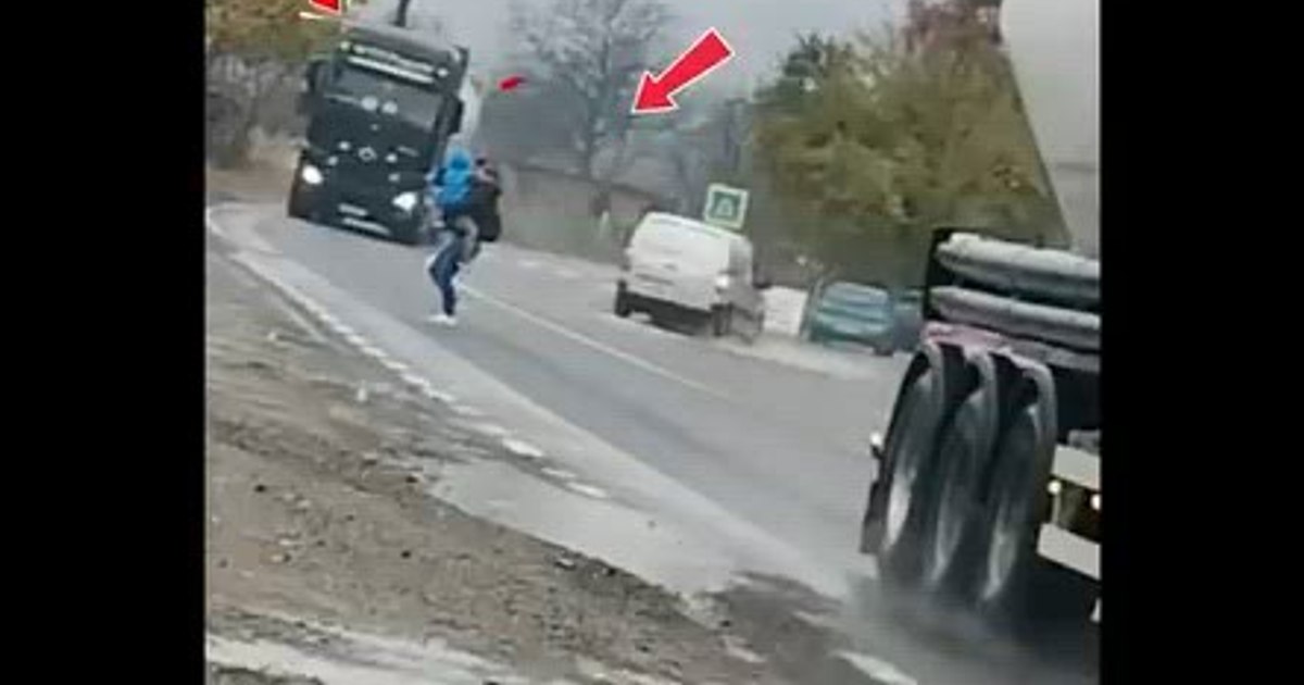 The unconscious gesture of a mother with a child in her arms: she rushes through the trucks, although there is a pedestrian crossing a few steps away